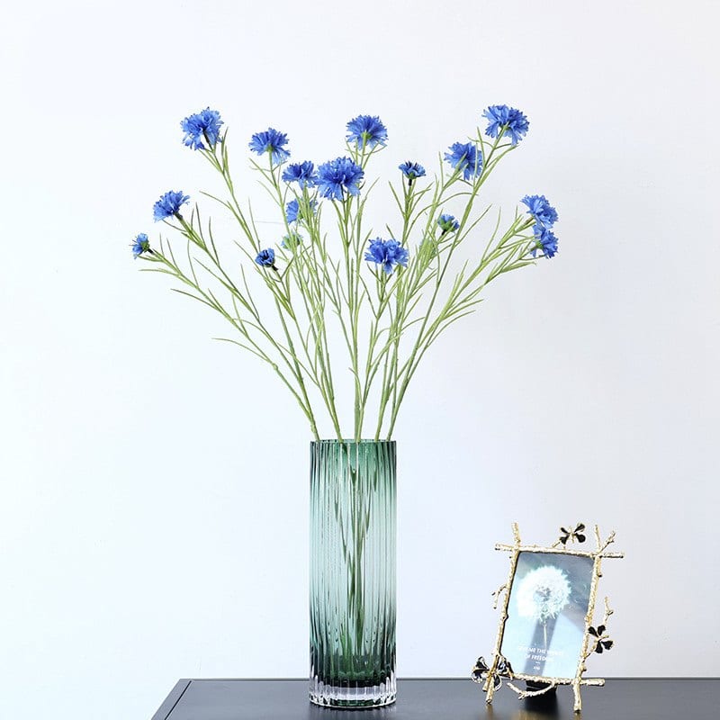 Bouquet de fleurs bleues artificielles dans un vase posé sur un meuble.