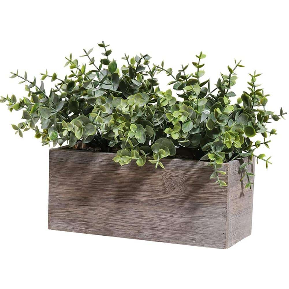 Plante artificielle verte dans un pot en bois rustique.