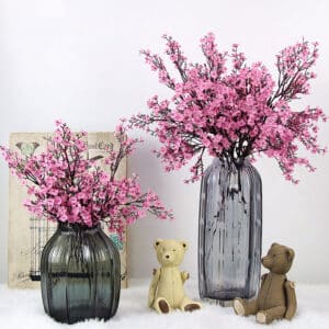 Deux vases contenant des bouquets de fleurs de cerisier. On voit également deux peluches oursons et un fond blanc.