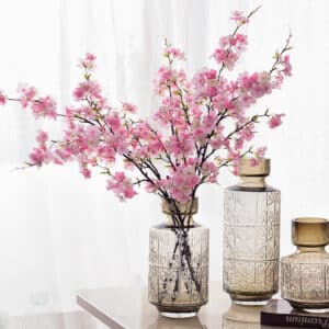 Fleurs de cerisier placées dans un vase posé sur une table.