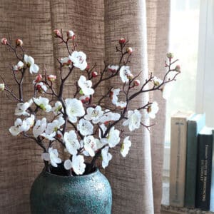 Vase contenant des fleurs de cerisier artificielles.