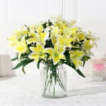 Bouquet de lys à fleurs jaunes dans un vase transparent.