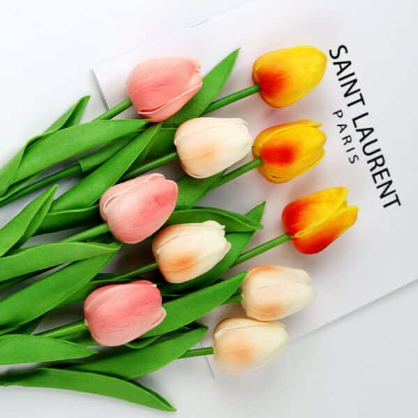 Tulipes blanches, roses et oranges posées sur un magazine blanc