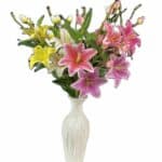 Vase remplit de fleurs de lys artificiel sur fond blanc.