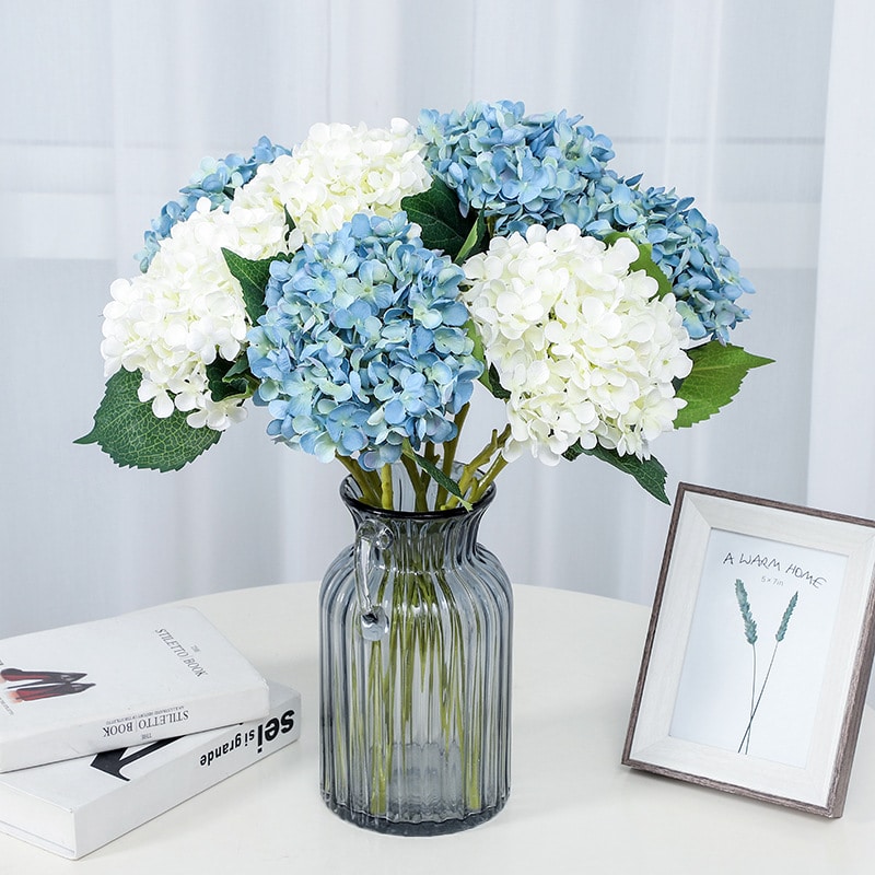 Bouquet de fleurs d'hortensia artificielles dans un vase posé sur une table.