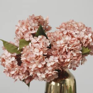 Bouquet d'hortensia artificiel rose dans un vase doré. Fond gris.