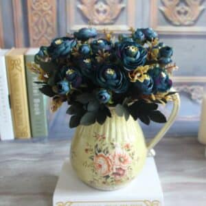 Bouquet de pivoines bleues dans un vase jaune posé sur une table.