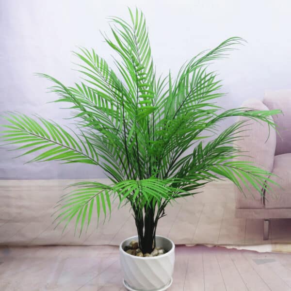 Feuilles de palmier dans un pot blanc devant un canapé