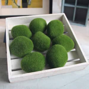 8 boules de mousse verte artificielle dans une petite cagette en bois blanche cérusée.