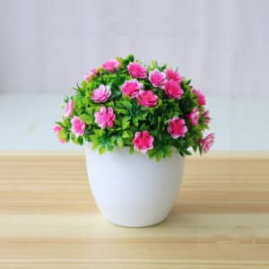 Petite plante artificiel dans un pot blanc avec des fleurs roses.