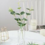Plante en feuille d'eucalyptus artificielle dans un vase sur un table blanche