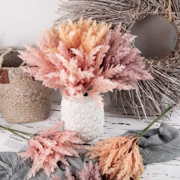 Photo de bouquet de roseaux artificielles de style bohème dans les tons rose et orange dans un décor rustique.