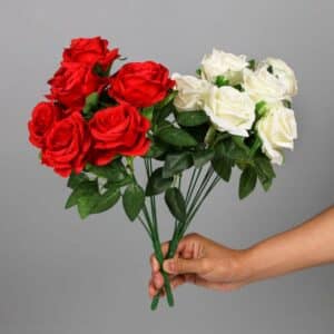 Une personne tient 2 bouquets de roses rouges et blanches devant un fond gris.